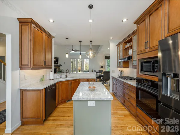a kitchen with stainless steel appliances granite countertop a sink a stove and a wooden cabinets