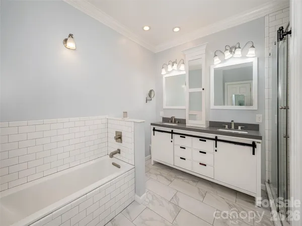 a bathroom with a tub sink double vanity and mirror