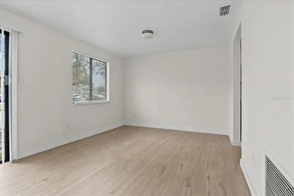 an empty room with wooden floor and windows