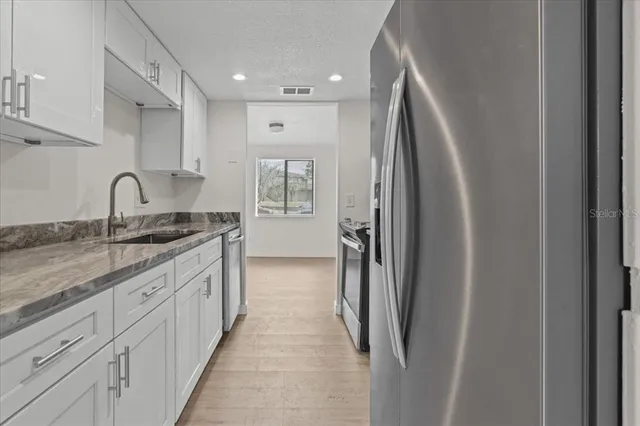 a kitchen with stainless steel appliances granite countertop a refrigerator and a sink