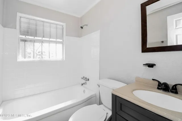 a bathroom with a granite countertop sink toilet a mirror and bathtub