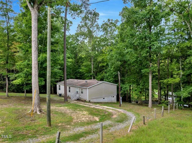 a backyard of a house with lawn chairs plants and large trees
