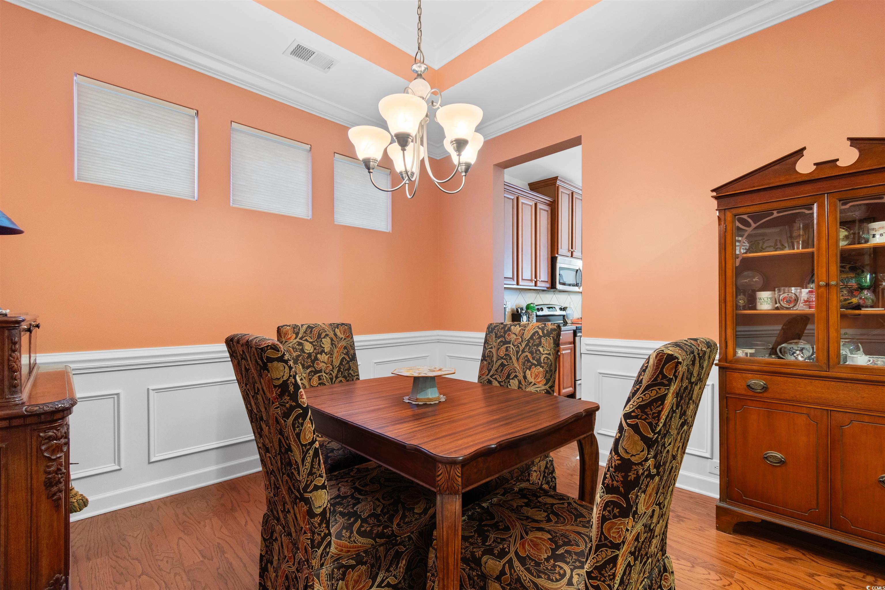1573 Culbertson Avenue Myrtle Beach, SC 29577 - Photo 21 of 40 Dining room with crown molding, light wood finished floors, a chandelier, a decorative wall, and wainscoting