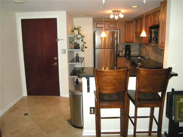 a kitchen with stainless steel appliances kitchen island granite countertop a refrigerator and a sink