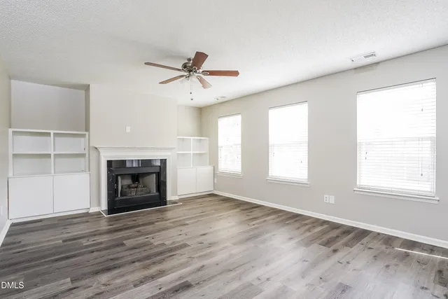 a view of empty room with wooden floor fireplace and fan
