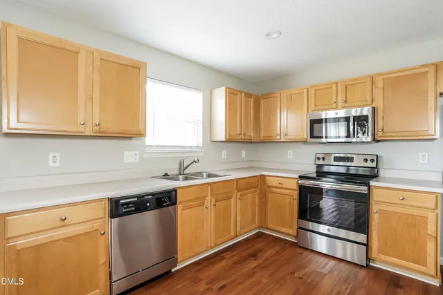 a kitchen with granite countertop wooden cabinets stainless steel appliances and a window