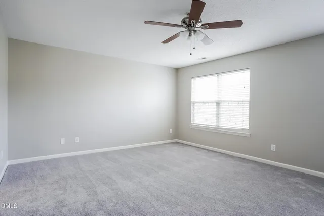 an empty room with a window and a fan
