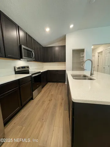 a large kitchen with a sink and dishwasher a stove with wooden floor