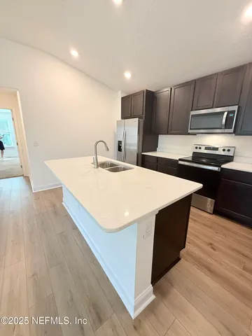 a kitchen with stainless steel appliances a kitchen island hardwood floor sink and stove