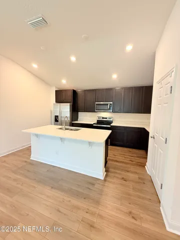 a large kitchen with kitchen island a sink wooden floor and a counter top space