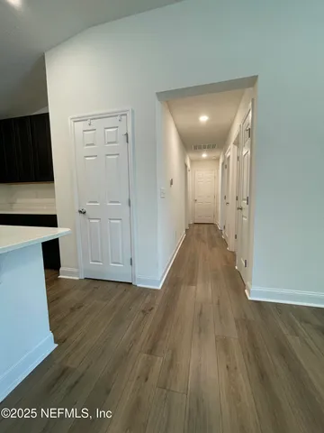 a view of a hallway to an empty room with wooden floor