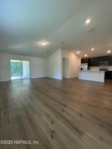 a view of an empty room with wooden floor