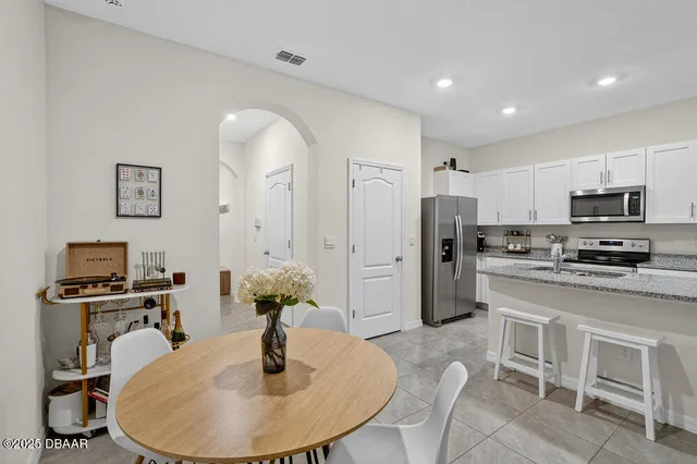 a kitchen with stainless steel appliances granite countertop a refrigerator a stove a sink a dining table and chairs