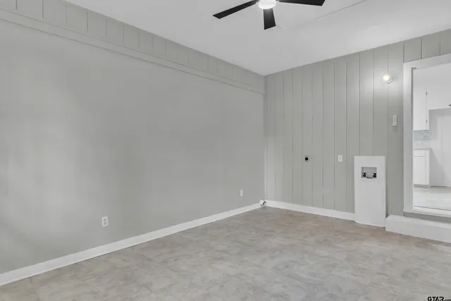 an empty room with ceiling fan and window