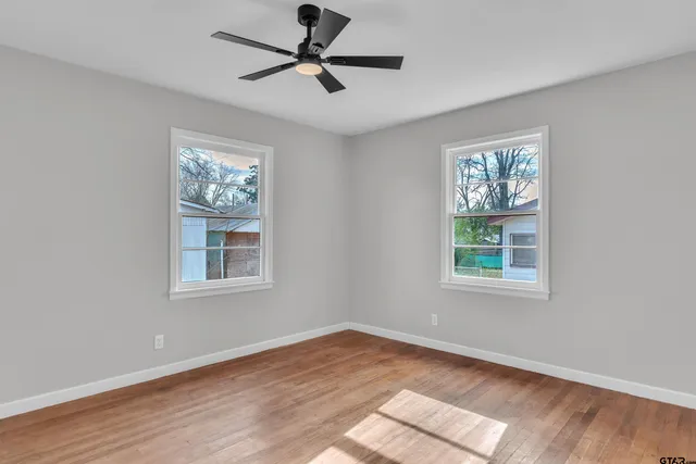 a view of an empty room with wooden floor and a window