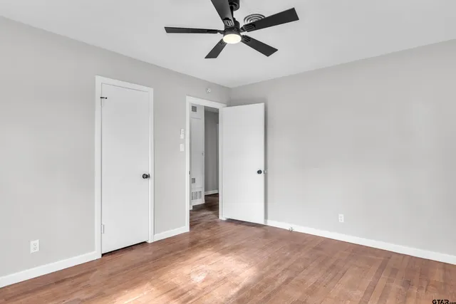 a view of a room with wooden floor and a ceiling fan