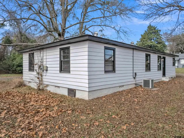 a backyard of a house with large tree and wooden fence