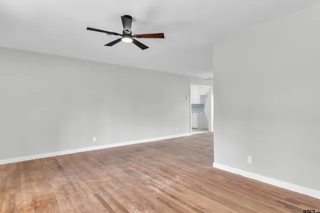 a view of a room with wooden floor and a ceiling fan