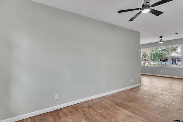 a view of an empty room with wooden floor and windows
