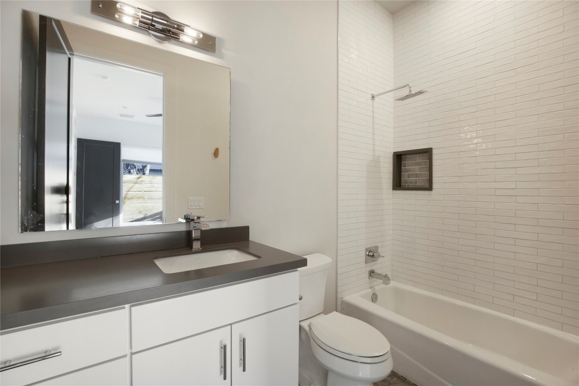 1708 Perez Street, Unit B Austin, TX 78721 - Photo 10 of 19 a bathroom with a granite countertop sink toilet a mirror and shower