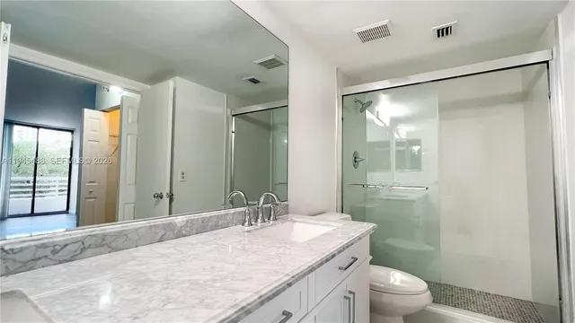 a bathroom with a granite countertop sink toilet and shower
