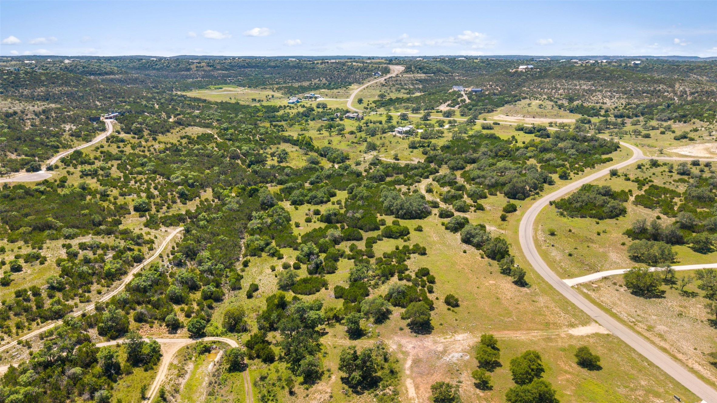 717 Bluff Ridge Trail Blanco, TX 78606 - Photo 8 of 21 Vast, verdant landscape unfolds with winding roads and distant homesteads, offering serene, pastoral views.
