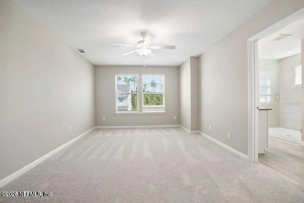 an empty room with chandelier fan and windows