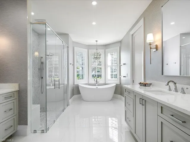 a bathroom with a double vanity sink a large mirror and a bathtub