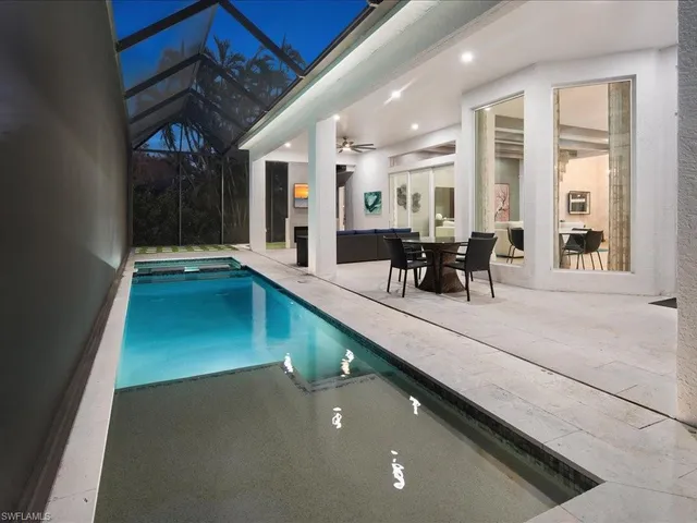 a dining hall with stainless steel appliances granite countertop a barbecue grill and couches with wooden floor