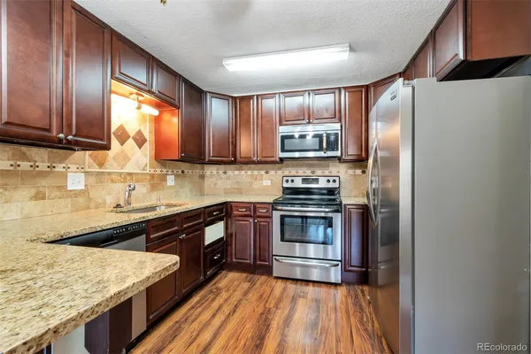 a kitchen with stainless steel appliances granite countertop a refrigerator a sink and wooden cabinets