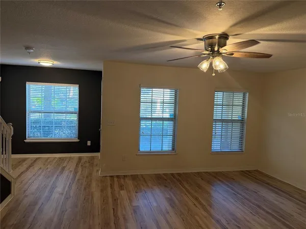 a view of an empty room with wooden floor and window
