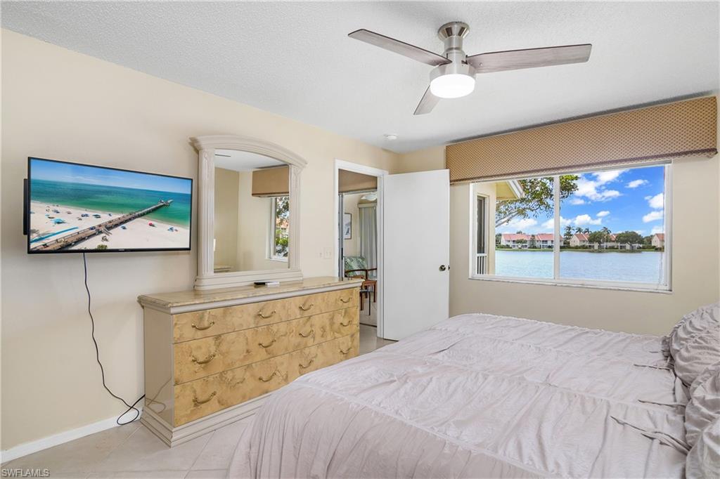 7754 Emerald Circle, Unit T202 Naples, FL 34109 - Photo 14 of 22 a bedroom with a bed and a painting on the wall