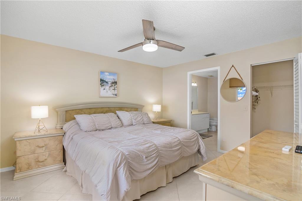 7754 Emerald Circle, Unit T202 Naples, FL 34109 - Photo 15 of 22 a bedroom with a bed and a chandelier