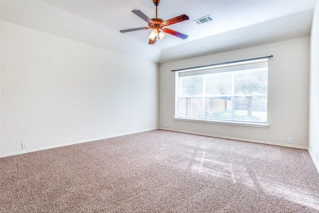 an empty room with windows and fan