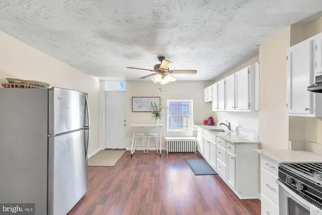 a kitchen with a refrigerator a stove cabinets and wooden floor