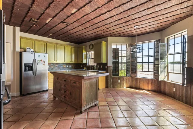 a large kitchen with kitchen island granite countertop a large window and stainless steel appliances
