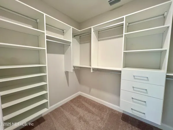 a view of walk in closet with empty racks