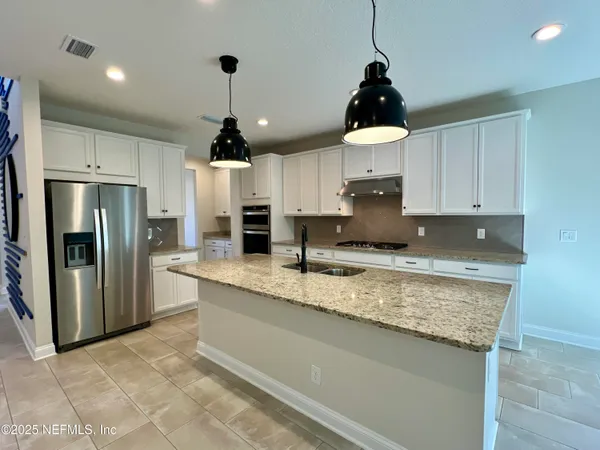 a kitchen with stainless steel appliances granite countertop a sink a refrigerator and a stove