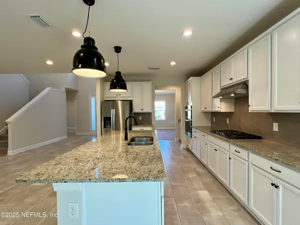a kitchen with stainless steel appliances granite countertop a sink a stove and cabinets