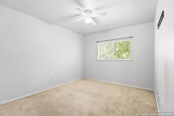 an empty room with a window and a fan