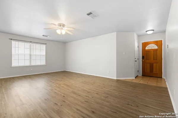 a view of an empty room with a window and wooden floor