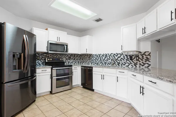 a kitchen with white cabinets appliances and a sink