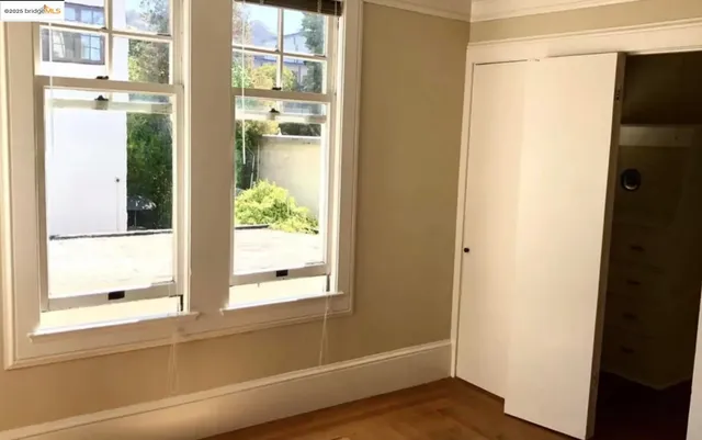a view of an empty room with wooden floor and a fireplace