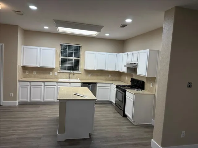 a kitchen with kitchen island granite countertop a sink cabinets and wooden floor