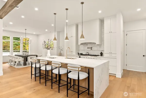 a kitchen with kitchen island stainless steel appliances a table chairs sink and wooden floor