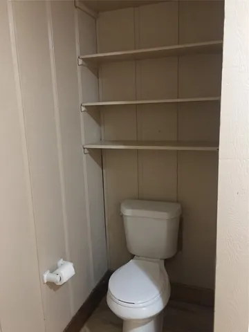 a white toilet sitting next to a small window