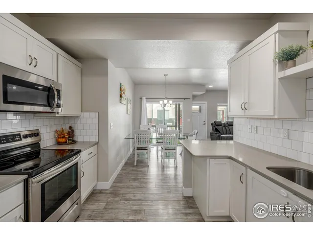 a kitchen with stainless steel appliances kitchen island granite countertop a sink dishwasher stove top oven and cabinets with wooden floor