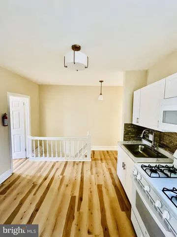 a large white kitchen with stainless steel appliances granite countertop a stove and a sink