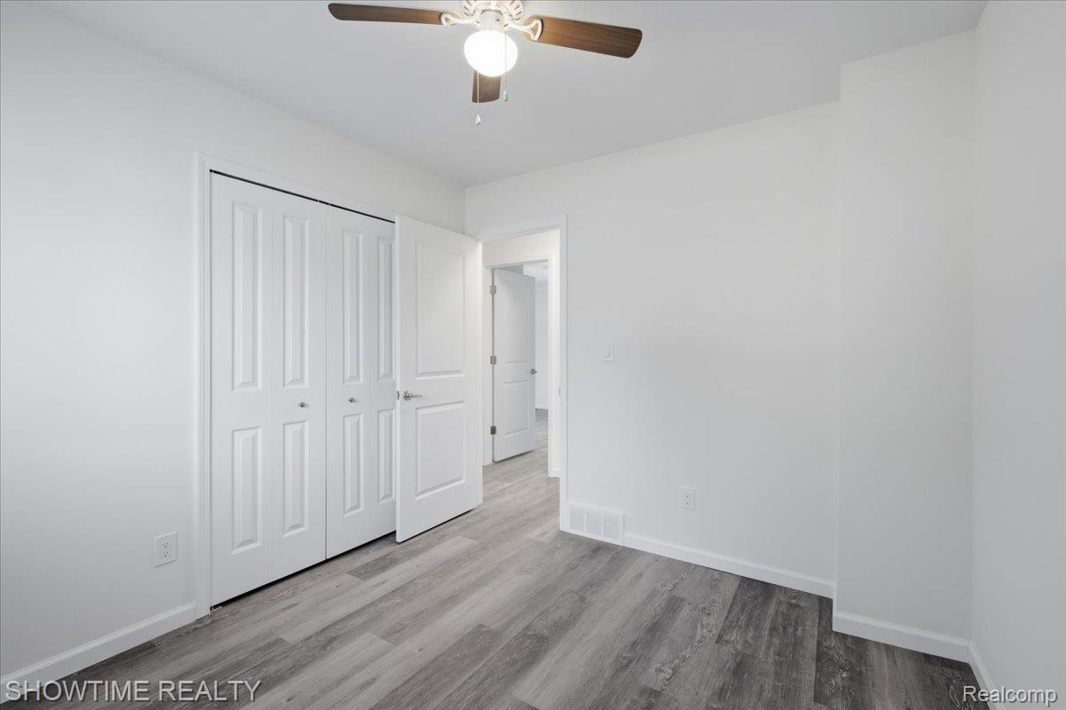 29255 Utley Road Farmington, MI 48334 - Photo 30 of 46 Neutral white walls, wood-finish flooring, white bi-fold closet doors, and an overhead ceiling fan