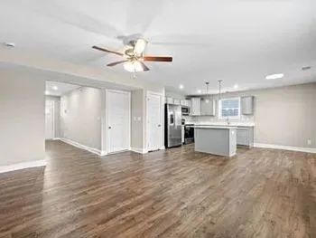 a view of a kitchen with a sink a kitchen island white cabinetry and a refrigerator